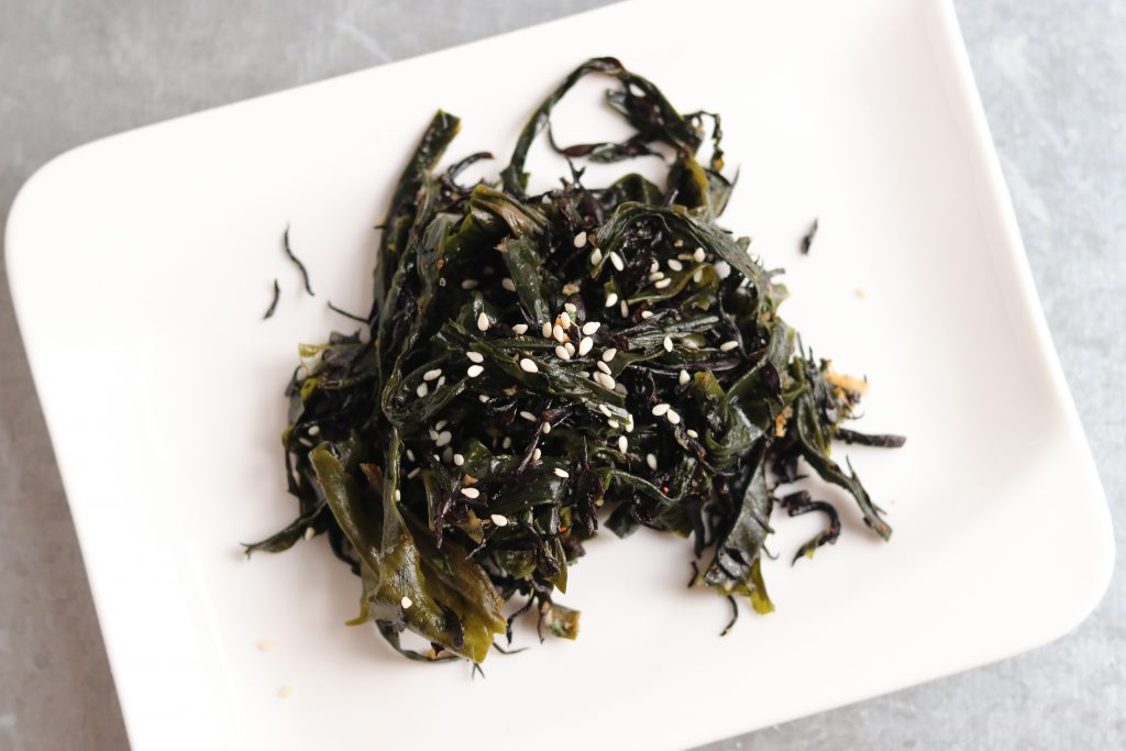 Japanischer Algensalat aus köstlichen Wakame Algen, mit Sesam bestreut auf einem Teller.