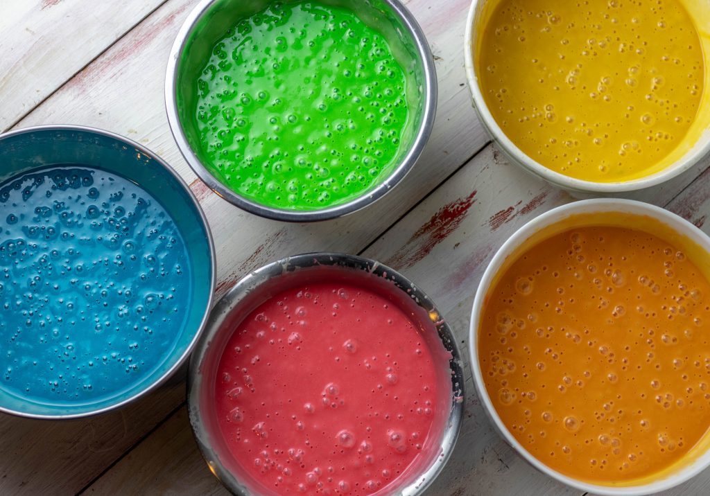 5 bunt mit Lebensmittelfarben eingefärbten Biskuitteige.