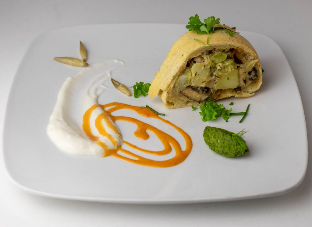 Ein Stück veganer Pot Pie mit Beilagen auf einem Teller.