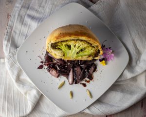 Broccoli baked in herbal dough on red wine shallots