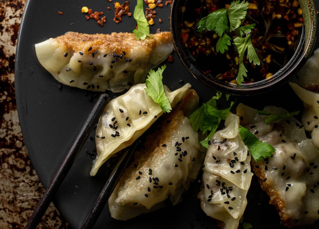 Gyoza sind köstliche, kleine japanische Teigtaschen, die mit einer herzhaften Flüllung aus Fleisch, Fisch oder Gemüse geformt werden.