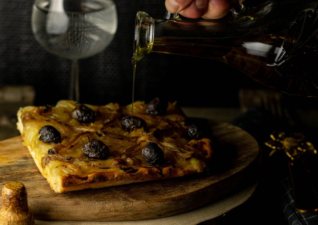Pissaladiere - französische Sardellen-Zwiebeltarte - Olivenöl wird darüber gegeben