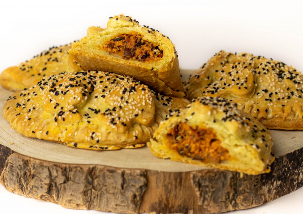 Hand Pies mit Waldpilzfüllung auf einem Holzbrett. Ein Pie sit aufgeschnitten.