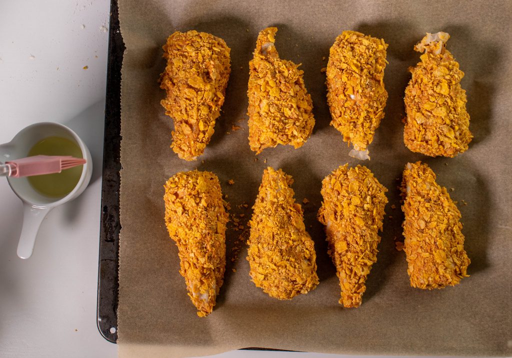 9. Vegane Hähnchenkeulen in Cornflakespanade auf einem Backblech ausbreiten, der Ofen heizt auf 180° vor