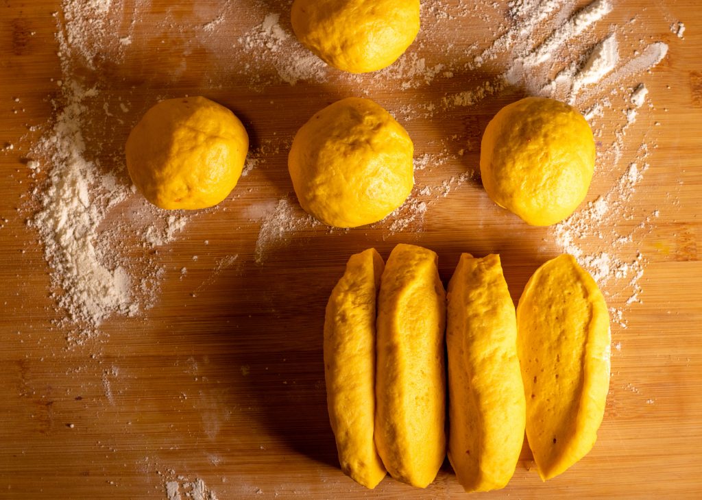 Kürbis-Brioche-Teig wird geteilt und in runde Brötchen geformt.