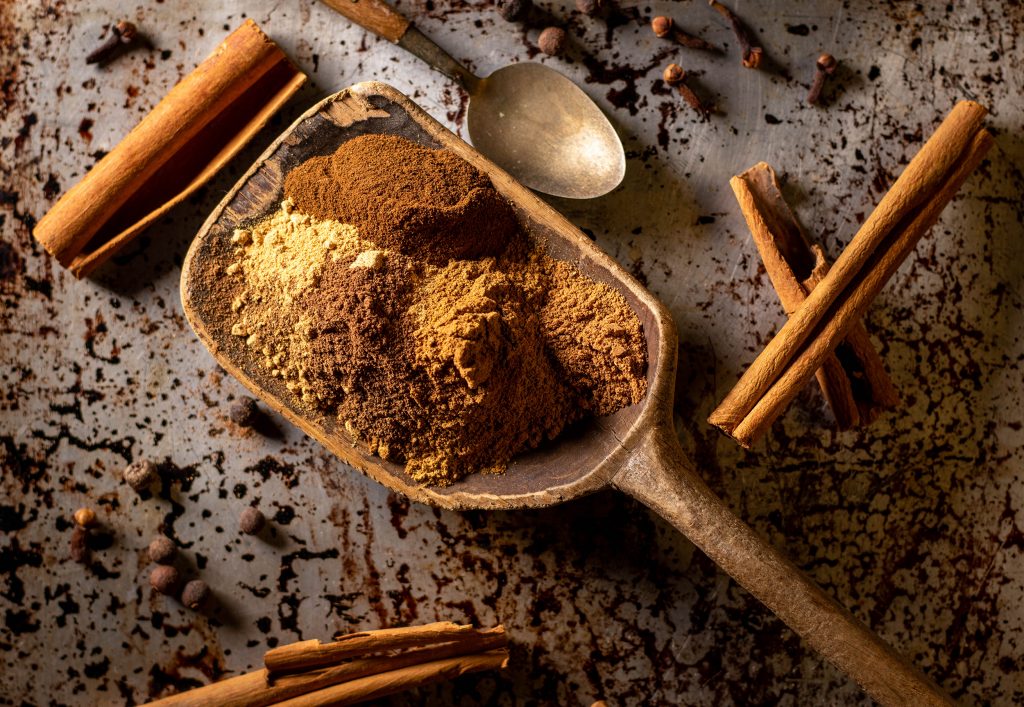 Alle Gewürze für Pumpkin Spice auf einem großen, alten Holzlöffel