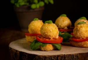 Frittierte Mozzarellabällchen - serviert auf Brot mit Tomate und Basilikum