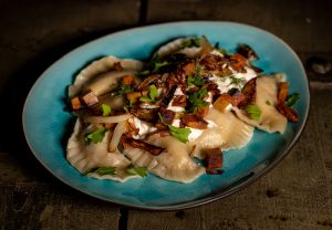 Vegane Piroggen mit veganer Sour Cream, gebratenen Zwiebeln und veganem Schinken