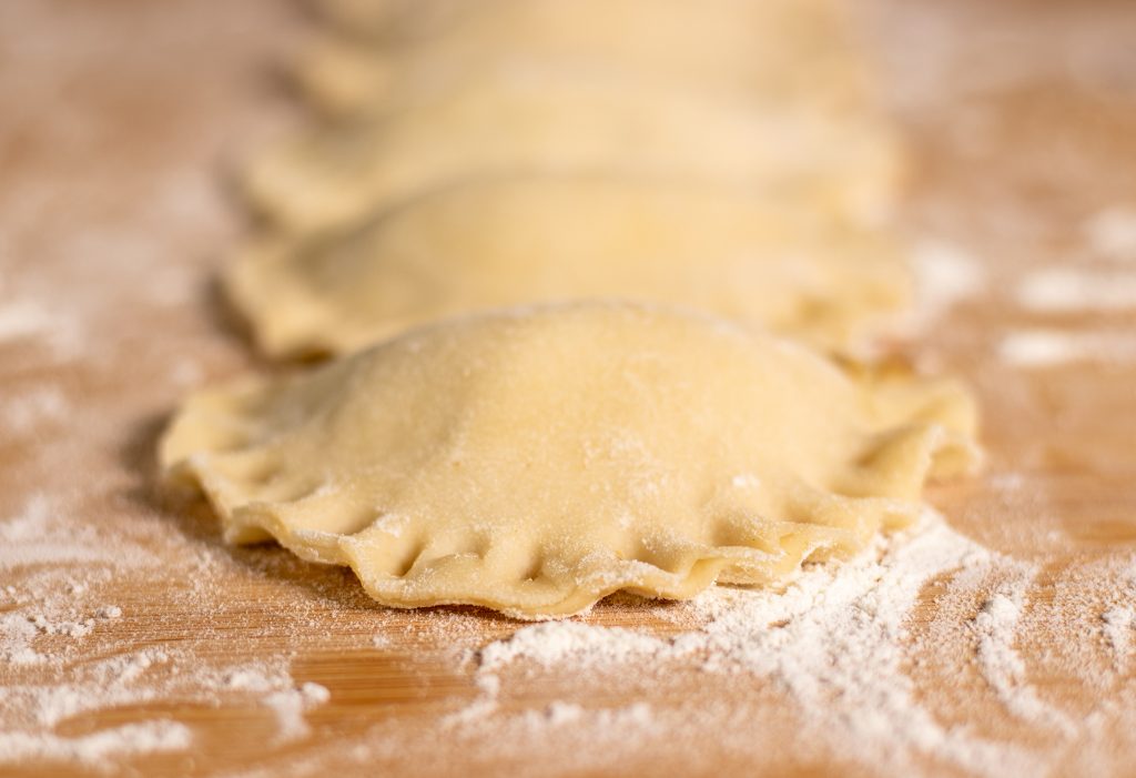 Gefüllte, rohe Pirogge mit fest geschlossenem, verziertem Rand