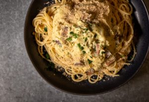 Vegane Spaghetti alla Carbonara auf schwarezem Teller