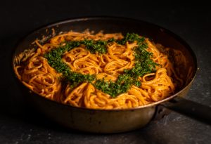 Spaghetti in roter Paprikasoße mit Kräuterherz garniert