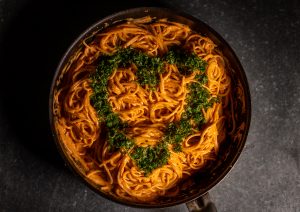 Spaghetti in roter Paprikasoße mit Kräuterherz garniert