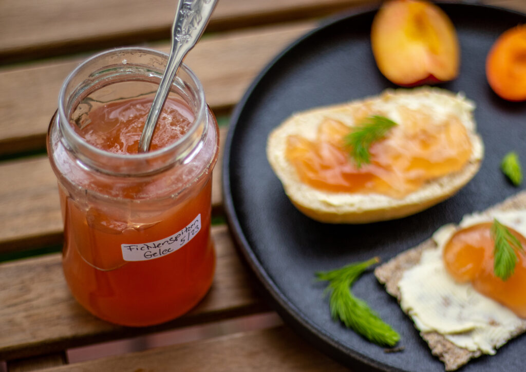 Selbstgekochtes Fichtenspitzengelee in einem Glas und auf Brot.