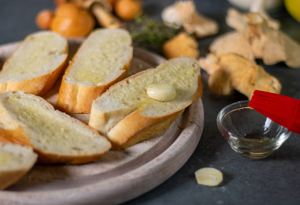 Zubereitung Veganes Pilzbruschetta: das Brot mit Öl und Knoblauch einreiben
