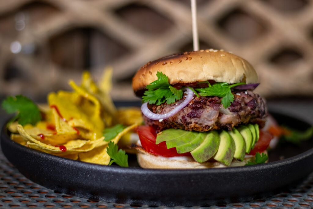 Veganer Bean Burger mit Tortilla Chips mit Keesesauce, dazu Salat