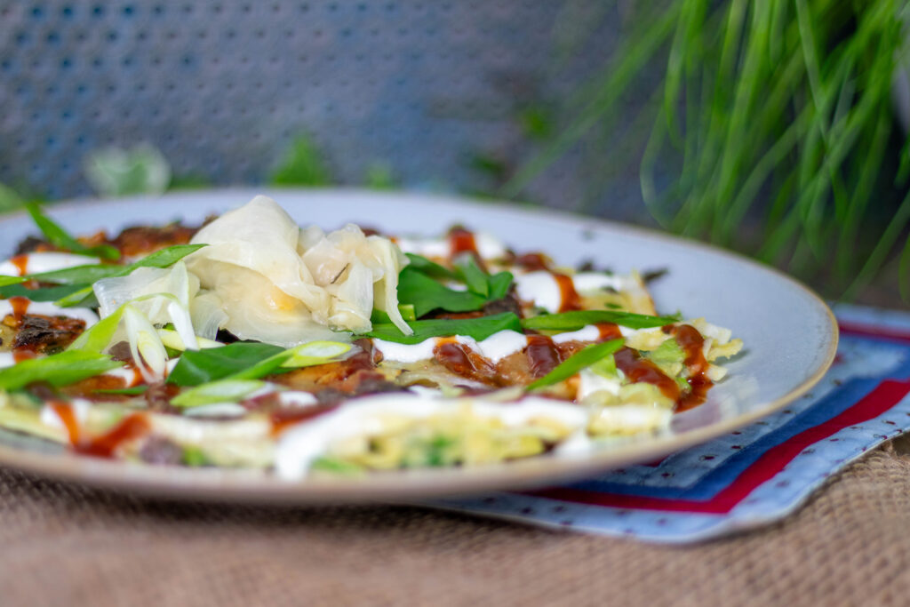 Okonomiyaki ist ein beliebtes japanisches Gericht, das oft als "japanischer Pfannkuchen" oder "japanischer Pizza" bezeichnet wird.