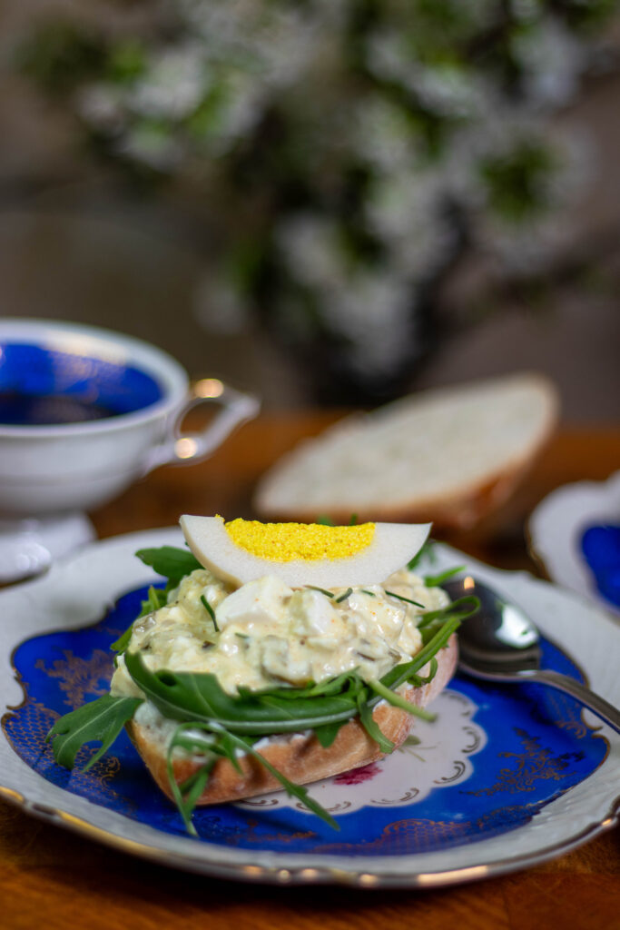 Sonntagsfrühstück: veganer Eiersalat auf Brötchen mit einem Viertel veganem, harten Ei