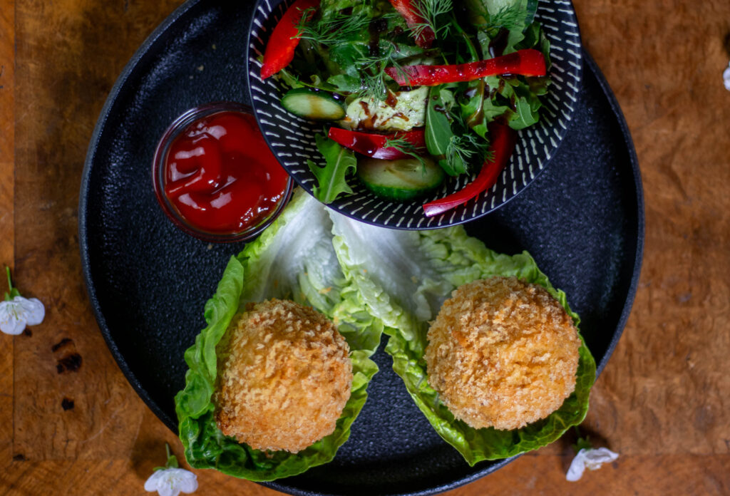 Vegane Mac'n'Cheese Bites mit selbstgemachter Keesesauce und knuspriger Panko-Panade sind ein gigantisch guter Snack. Hier zu sehen mit Salat und Ketchup.