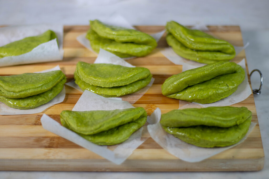 7. Die eingefetteten rohen Bao Buns werden gefaltet und auf Backpapier platziert.