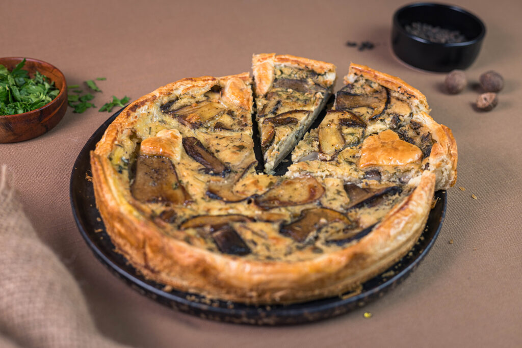 Steinpilzquiche, angeschnitten, auf einem Teller.