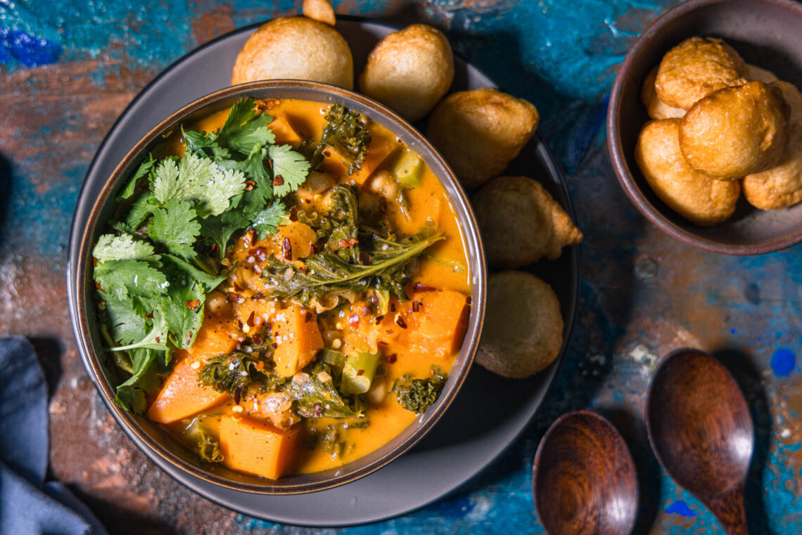 West African peanut stew with puff puffs, garnished with fresh coriander