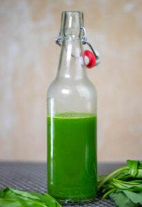 Green wild garlic oil in a bottle. Fresh wild garlic next to the bottle.