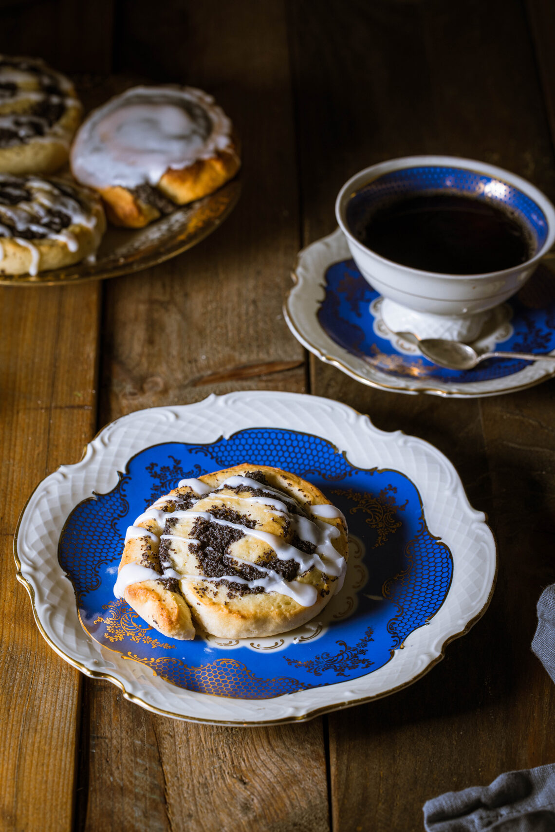 Mohnschnecken - vegan - auf einem Holztisch mit einer Tasse Kaffe und antikem Sammelgeschirr.