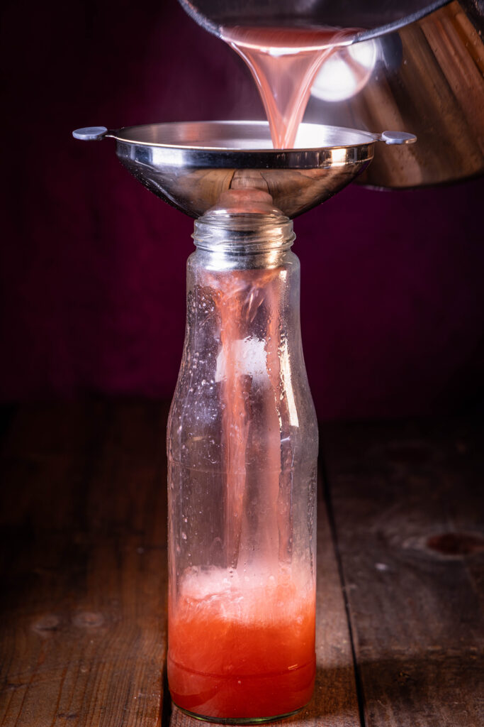 Rhabarber-Ingwer-Bitter-Sirup wird kochend heiß in eine Flasche abgefüllt.