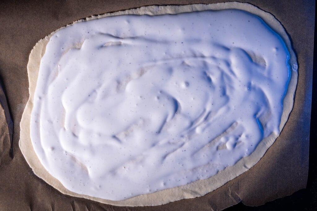 Flammkuchenteig belegt mit veganer Flammkuchencreme