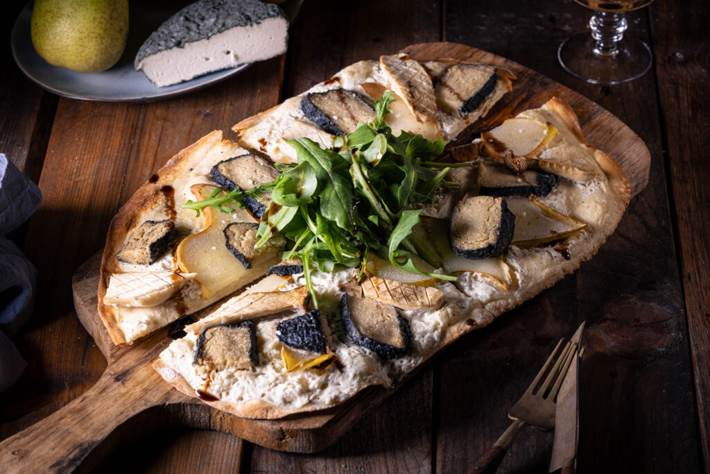 Veganer Flammkuchen mit Blauschimmelkäse, Birne, Kräuterseitlingen, Rucola und einem Spritzer Crema de Balsamico