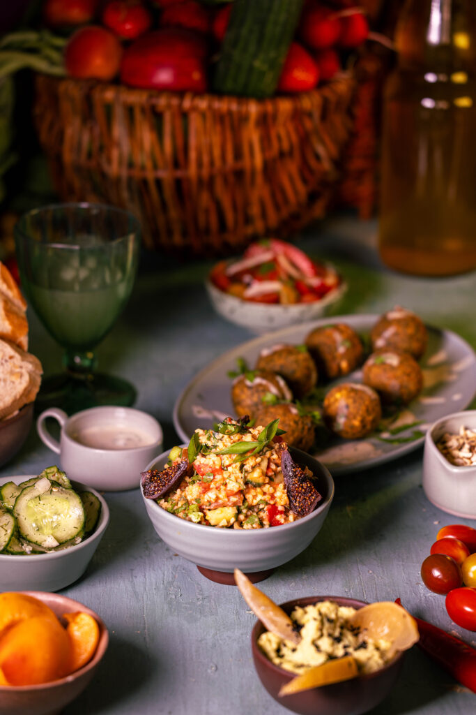 Mein Bulgursalat ist auch köstlich als Mezze. Hier mit Hummus, Gurkensalat mit Kokoskefirdressing, Falafel, Tomaten-Petersilien-Salat, Tahinisauce, Nüssen, Obst und Brot.