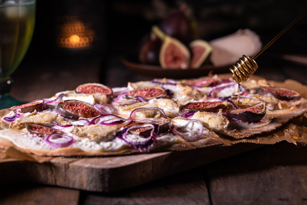 Veganer Flammkuchen mit Camembert und Feige - Dazu selbstgemachter, veganer Honig, der auf dem Foto darauf gegträufelt wird.