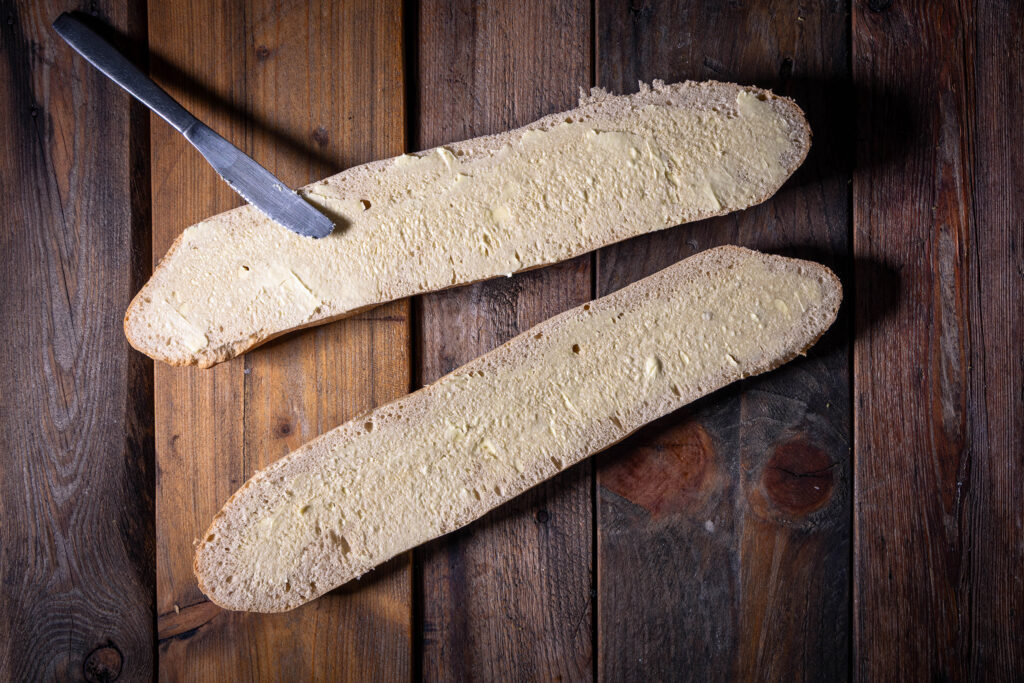 Ein Baguette wird mit veganer Butter bestrichen.