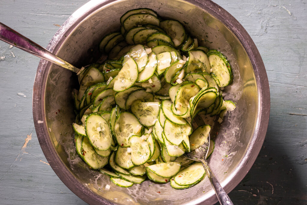 Gurkensalat wird in einer Schüssel vermengt.