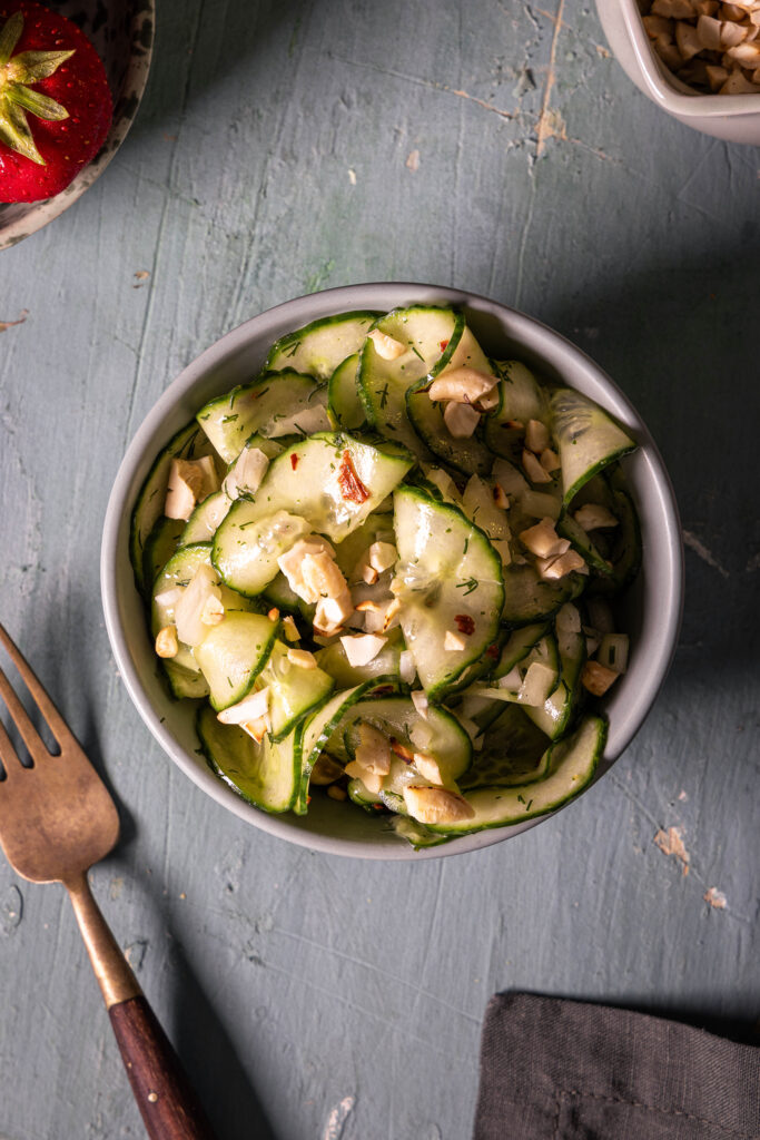 Gurkensalat mit Kokoskefirdressing - in einer Schale auf einem grünen Tisch