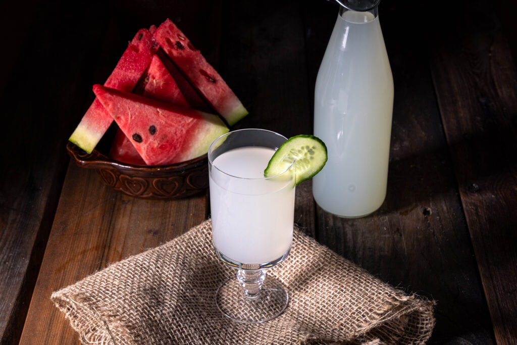Ingwer-Bitterlemon-Kefir in einem Glas und in iner Flasche, außerdem eine Schlae Melonenstücke.