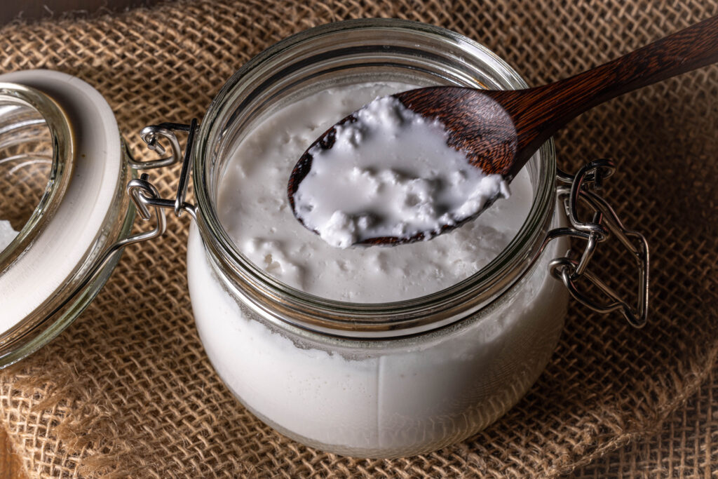 Der Kefir ist fertig, er hat die Konsistenz und den Geschmack der Kokosmilch stark verändert. Auf einem Löffel sieht man hier flockige Kokosmilch.