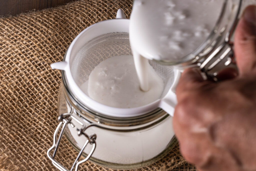 Vegaenr Kefir wird durch ein Plastiksieb abgeseiht.