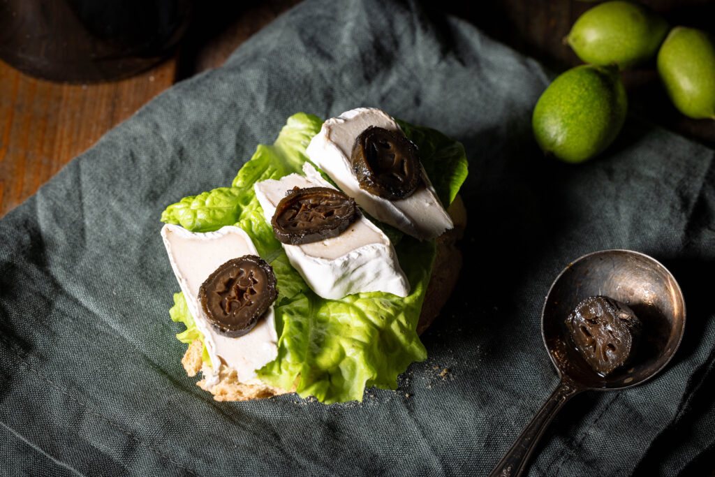 Süß-sauer eingelegte Schwarze Nüsse auf einem Brot mit veganem Camembert