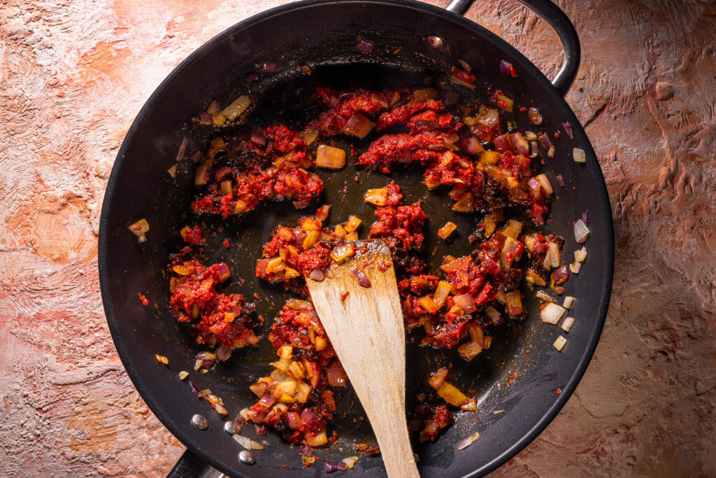 Zwiebeln, getrocknete Tomaten und Tomatenmark braten in einer Pfanne
