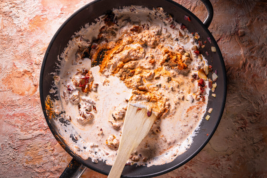 Eine sahnige Sauce wird in einer Pfanne angerührt.