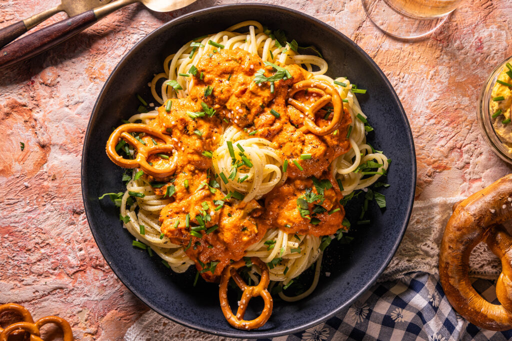 Spaghetti al Camembert mit Obazda-Sauce - auf einem Teller mit kleinen Brezeln