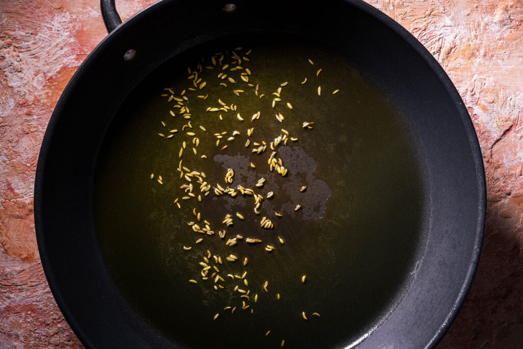 Fenchelsamen braten in Olivenöl in einer Pfanne.