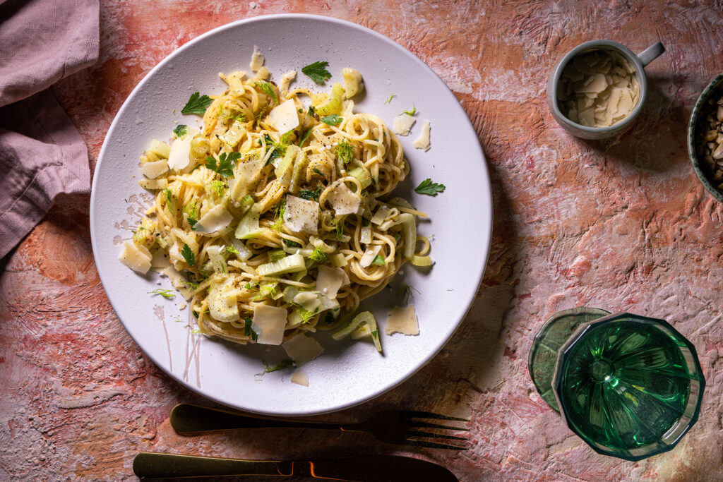 Fenchel Spaghetti, mit Knoblauch und Zitrone. Auf einem Teller angerichtet, mit veganem Parmesan bestreut.