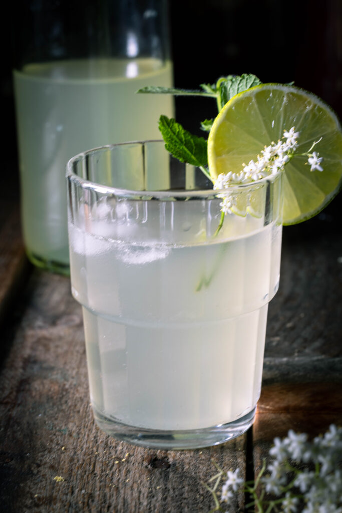 Holunderblütenkefir im Glas, dahinter in einer Flasche.