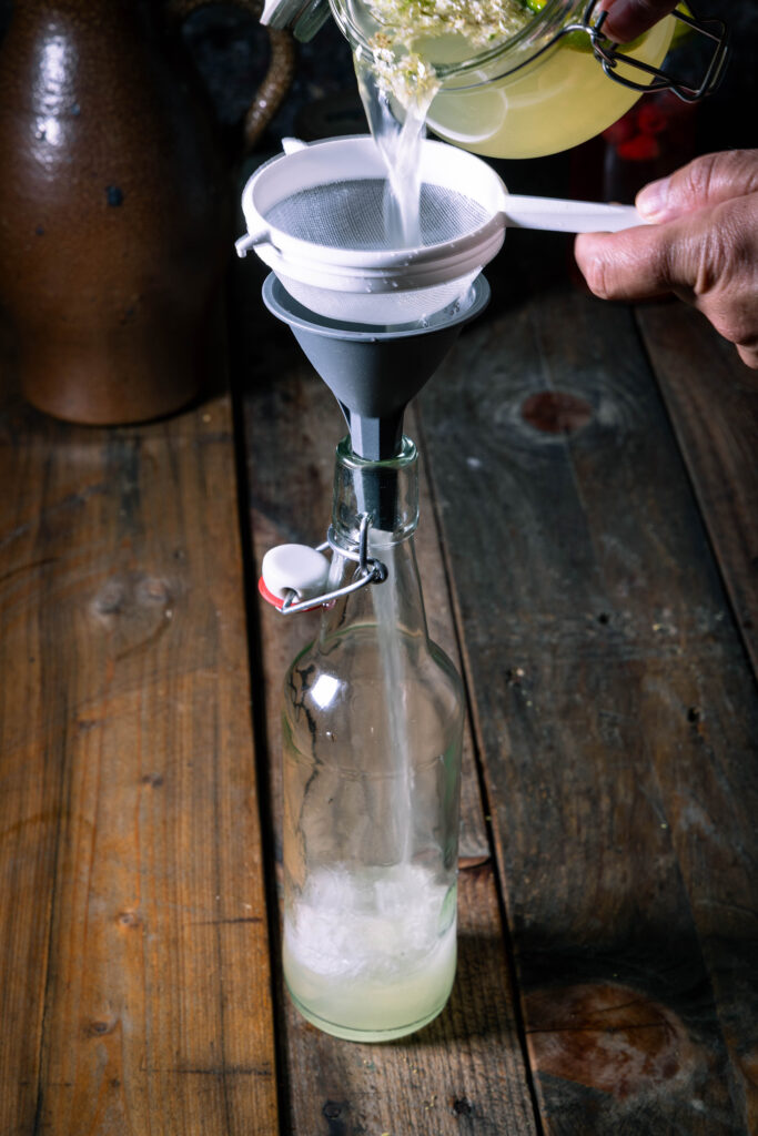 Zweitfermentierter Wasserkefir wird in eine Flasche abgeseiht.