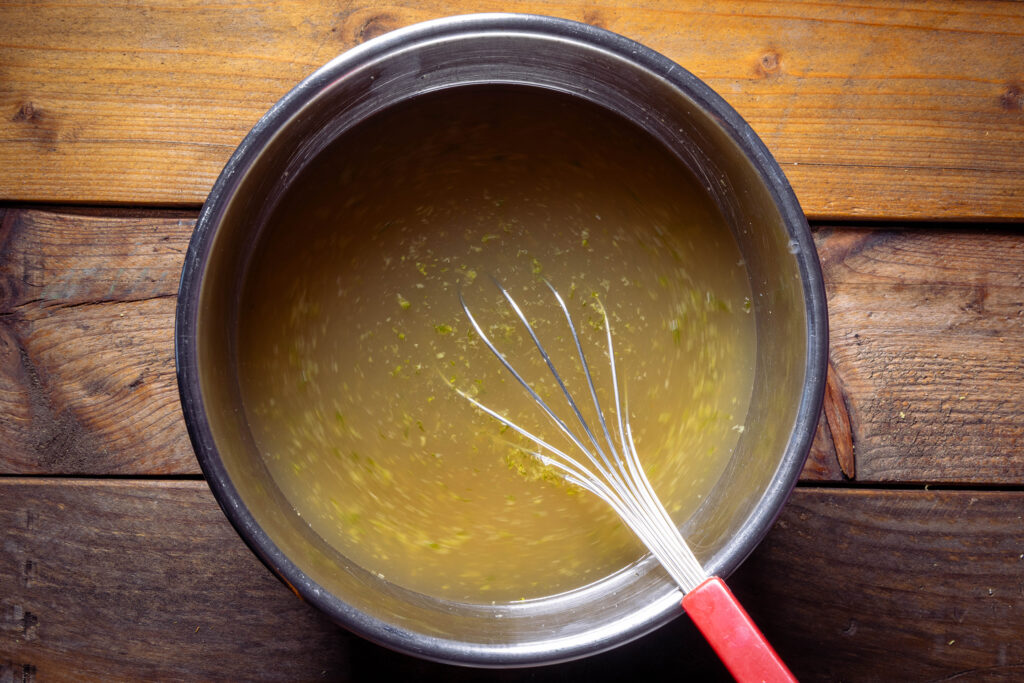 Kombucha, Limettensaft und Limettenabrieb werden in Zuckersirup gerührt.