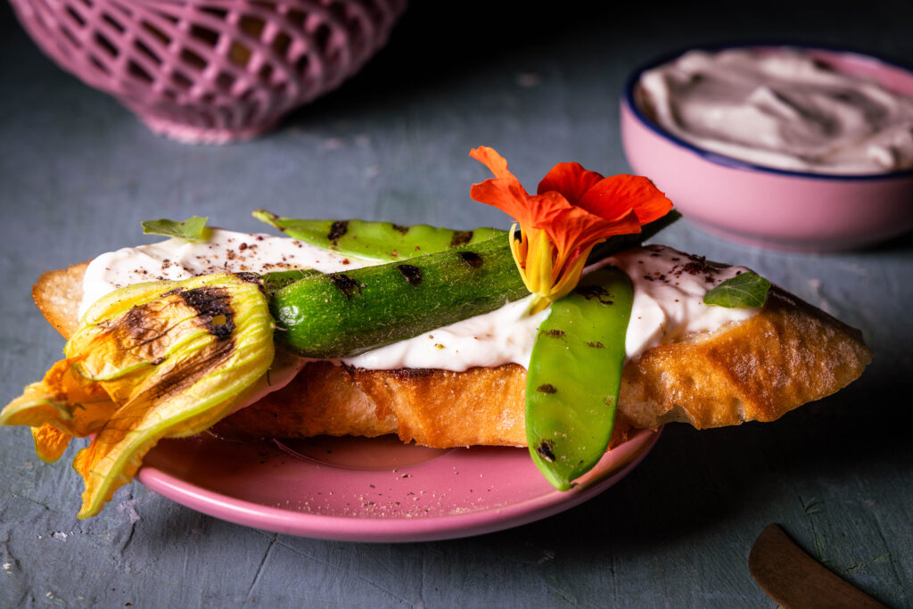 Eine Scheibe Brot mit einer gerösteten Babyzucchini und Vrischkäse