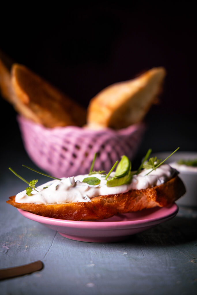 Vrischkäse - veganer Frischkäse mit Kräutern auf einem Stück Brot.