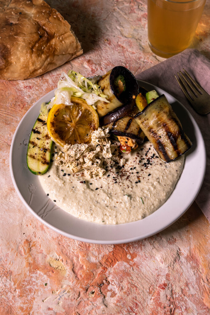 Veganer Auberginen-Schafskäse-Dip, Auberginen-Veta-Creme, mit verschiedenen Beilagen auf einem Teller.